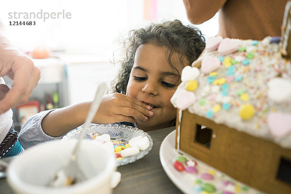 Kleines Mädchen knabbert Süßigkeiten für Weihnachten Lebkuchenhaus