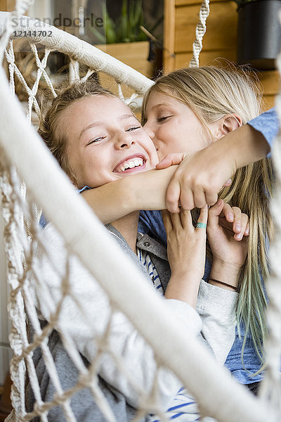 Mädchen umarmen und küssen ihre beste Freundin in einem Hängestuhl