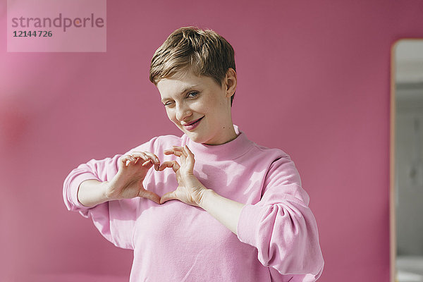 Porträt einer Frau in rosa funkelndem  formendem Herzen mit ihren Händen