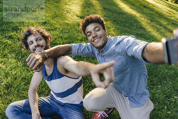 Zwei glückliche Freunde  die für einen Selfie in einem Park posieren.
