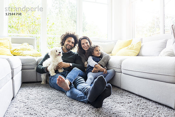 Fröhliche Familie mit Hund im gemütlichen Wohnzimmer