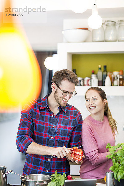 Ein glückliches junges Paar bereitet eine gesunde Mahlzeit in der Küche zu.