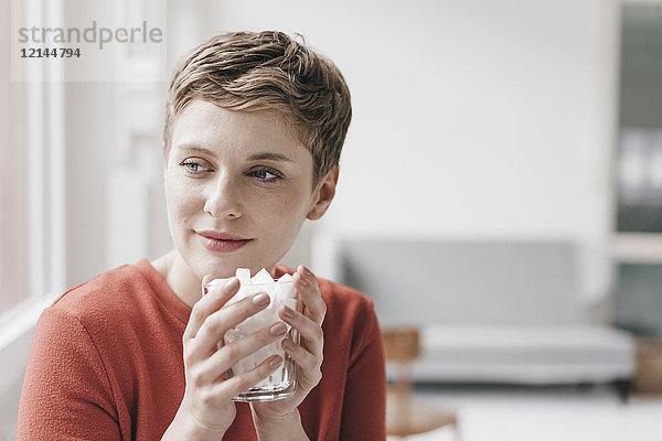 Lächelnde Frau hält Glas voll mit Zuckerwürfeln