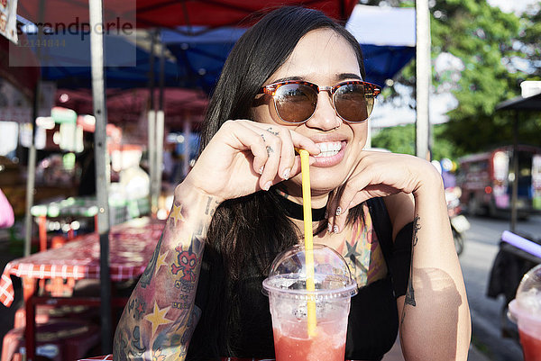 Porträt einer glücklichen Frau  die einen Smoothie im Freien trinkt.