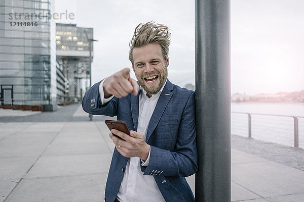 Porträt eines glücklichen Geschäftsmannes mit Handy in der Stadt