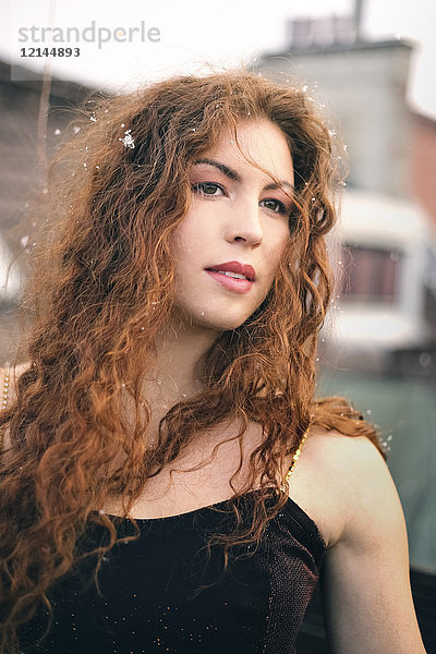 Porträt einer rothaarigen jungen Frau mit Schneeflocken auf den Haaren