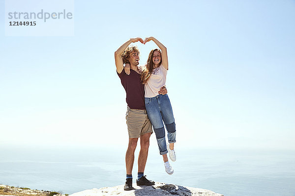Südafrika  Kapstadt  glückliches junges Paar auf einem Berg an der Küste