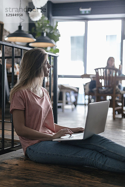 Junge Frau sitzend im Café  mit Laptop