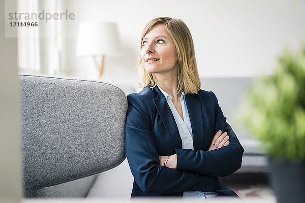 Lächelnde Geschäftsfrau sitzend auf der Couch in der Bürolounge