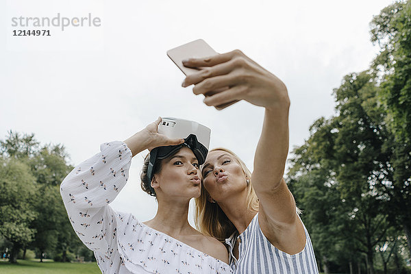 Zwei junge Frauen mit VR-Brille  die einen Selfie im Park mitnehmen.