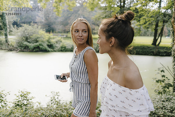 Zwei junge Frauen mit Handy an der Uferpromenade