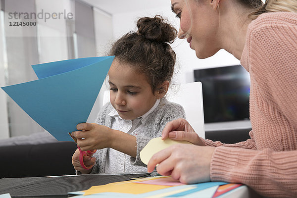 Mutter und kleine Tochter basteln mit farbigem Effektpapier