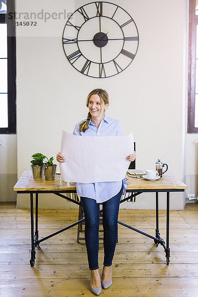 Lächelnde Frau im Home-Office mit Blaupause