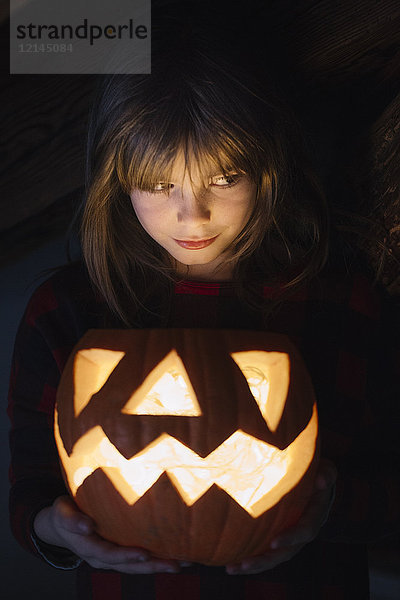 Porträt eines Mädchens mit beleuchteten Jack O'Lantern an Halloween