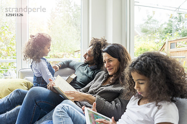 Glückliche Familie auf der Couch sitzend  Bücher lesend