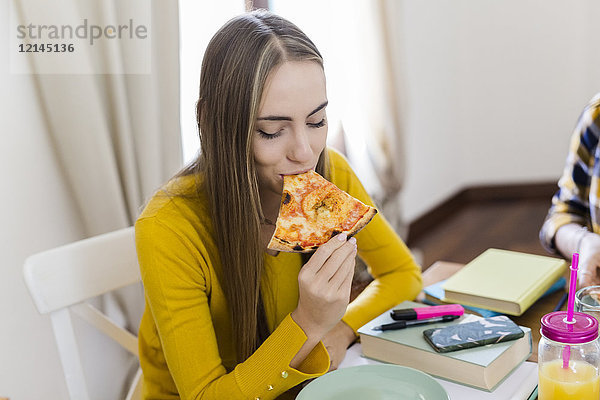 Junge Frau zu Hause studieren und Pizza essen