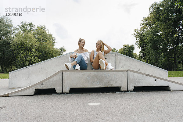 Zwei junge Frauen  die in einem Skatepark reden.