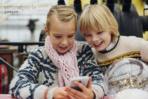 Bruder und Schwester senden SMS mit Weihnachtswünschen auf dem Smartphone