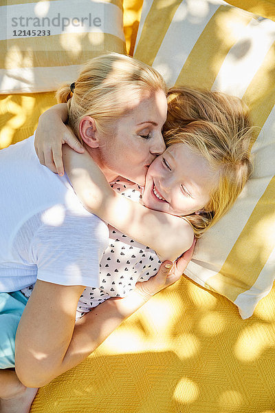 Glückliches Mädchen und Mutter umarmend und küssend auf einer Decke