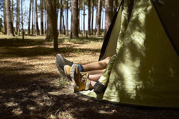 Schuhe ragen aus einem Zelt im Wald.