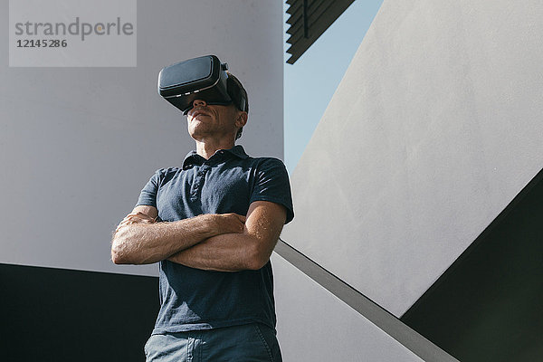 Erwachsener Mann mit VR-Brille zwischen Wänden moderner Architektur
