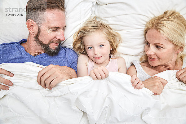 Porträt einer lächelnden Familie im Bett liegend