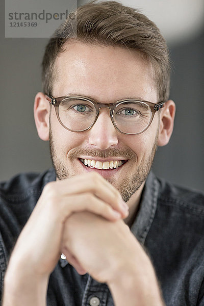 Porträt eines lächelnden jungen Mannes mit Brille