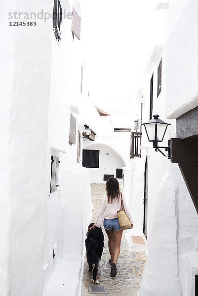 Spanien  Menorca  Berner Sennenhund im Sommer neben seinem Hundebesitzer in einem kleinen weißen Dorf