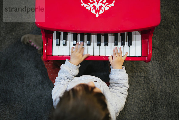 Kleines Mädchen spielt zu Hause Klavier  von oben