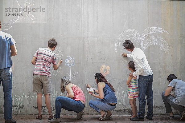 Menschen  die bunte Bilder mit Kreide auf einer Betonwand zeichnen