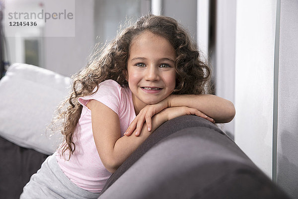 Porträt des lächelnden Mädchens mit Zahnlücke auf der Couch