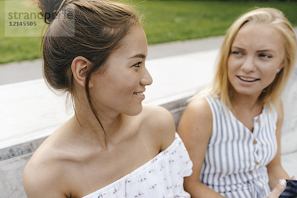 Zwei lächelnde junge Frauen sprechen im Freien