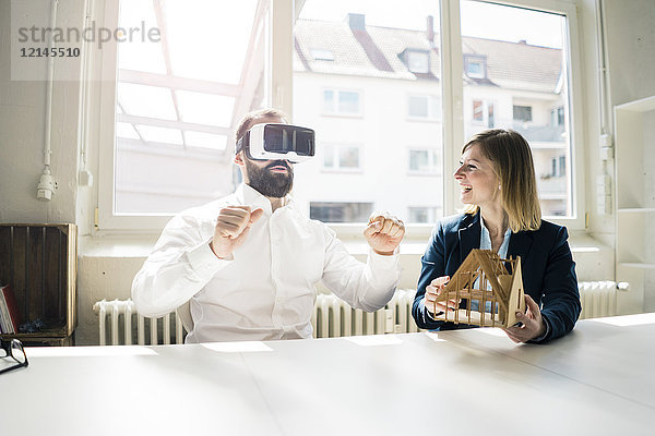 Frau und Mann mit Hausmodell und VR-Brille im Büro