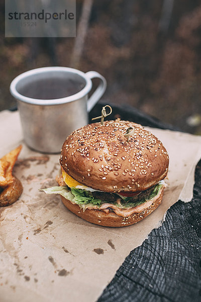 Burger und Becher mit Tee auf Briefmarke