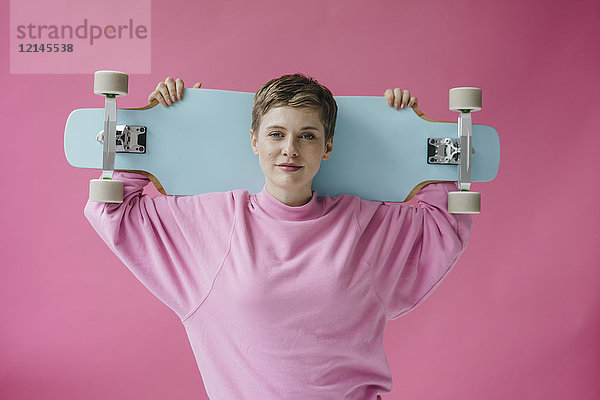 Porträt der Frau in rosa mit Skateboard