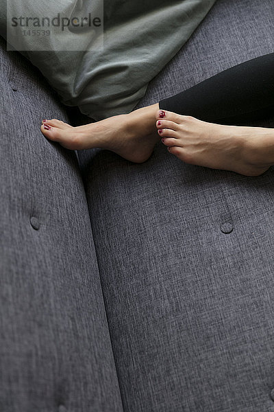 Füße einer Frau  die zu Hause auf der Couch liegt.