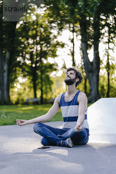 Mann im Skatepark sitzend meditierend