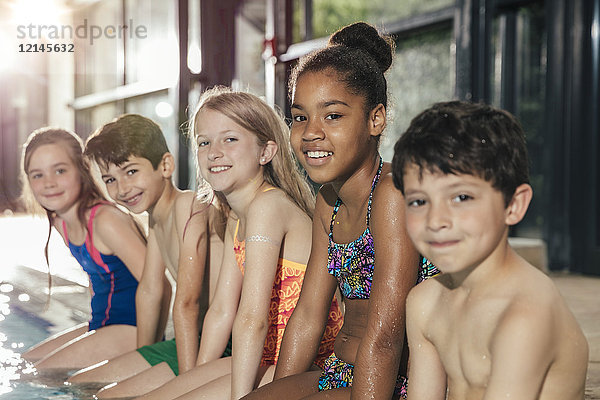Porträt der lächelnden Kinder am Pool im Hallenbad