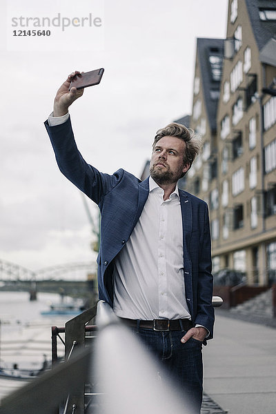 Geschäftsmann mit einem Handy-Selfie am Flussufer