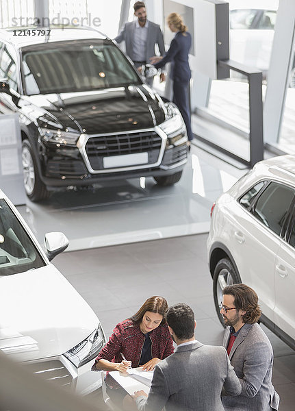 Autoverkäufer und Kunden im Autohaus Showroom