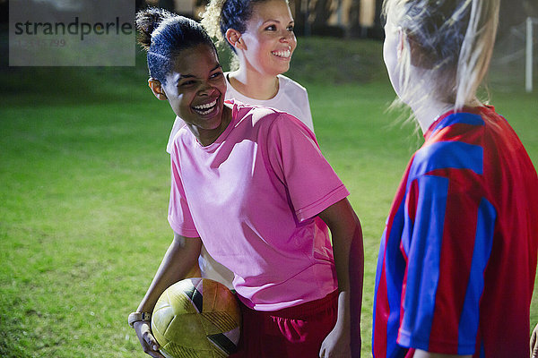 Verspieltes  lachendes  junges weibliches Fußballspiel auf dem Spielfeld bei Nacht