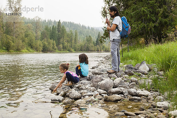 Vater und Töchter beim Wandern  Ausruhen am Seeufer