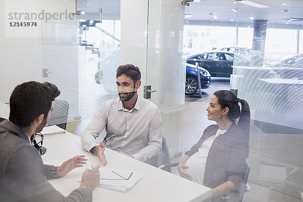 Schwangeres Paar im Gespräch mit dem Autoverkäufer  Besprechung des finanziellen Papierkrames im Autohausbüro