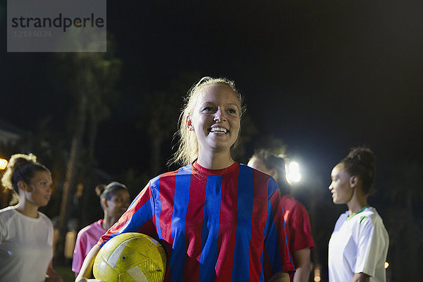 Portrait lächelnde  selbstbewusste junge Fußballspielerin mit Ball
