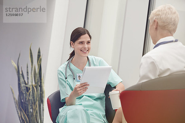 Lächelnde Krankenschwester mit Klemmbrett im Gespräch mit dem Arzt im Krankenhaus