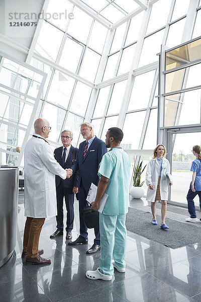 Begrüßung des Chirurgen  Händeschütteln mit den Geschäftsleuten des Verwalters in der Lobby des Krankenhauses
