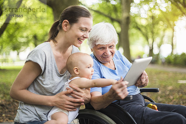Großmutter  Tochter und Enkelin haben Spaß mit Tablette im Park