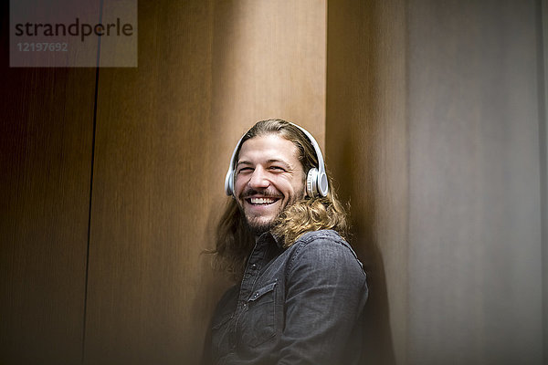 Porträt des lachenden Mannes beim Musikhören mit Kopfhörern