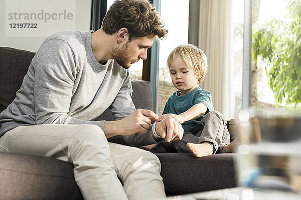 Sohn untersucht Vaters Smartwatch auf der Couch zu Hause