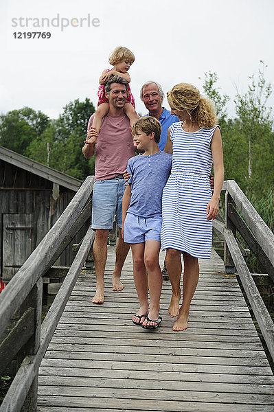 Glückliche Familie beim gemeinsamen Spaziergang auf der Strandpromenade im Sommer